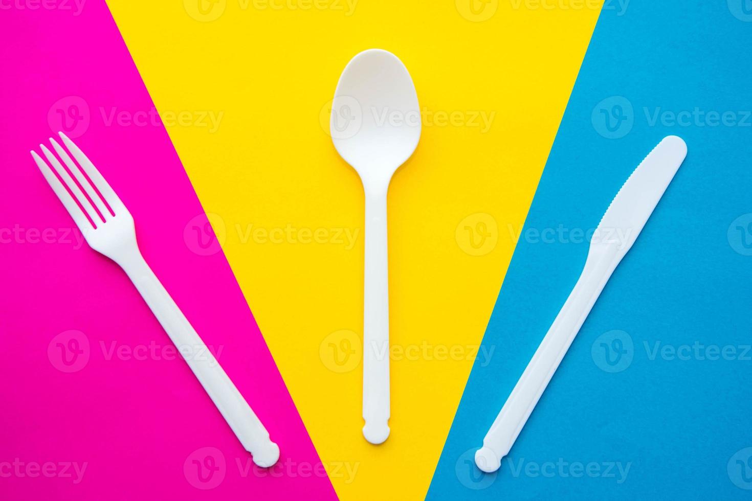 tenedor, cuchara y cuchillo de plástico blanco sobre fondo multicolor foto