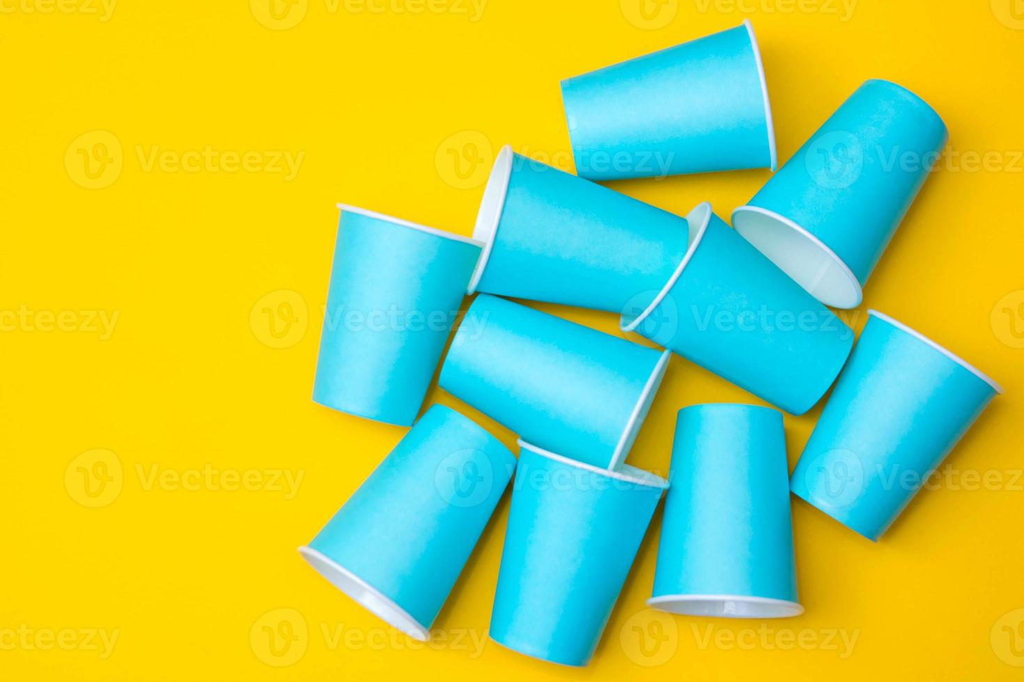 Muchos vasos desechables de papel azul sobre fondo amarillo foto