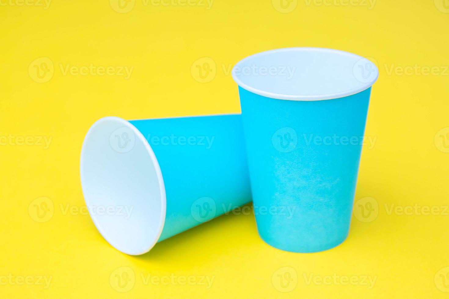 dos vasos de papel azul sobre fondo amarillo foto