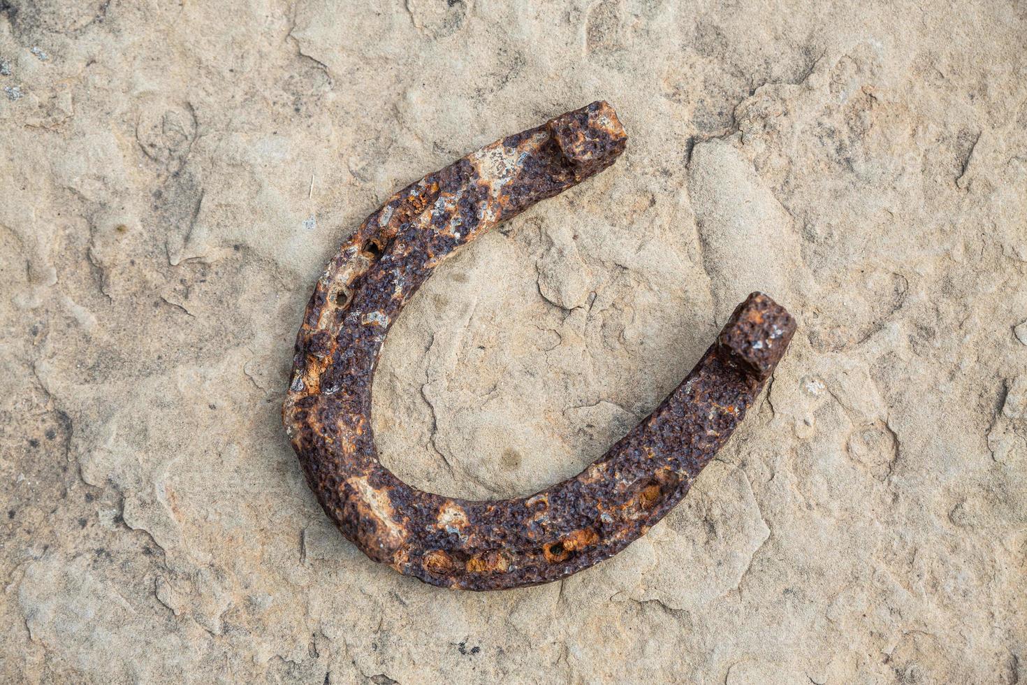 primer plano de una vieja herradura oxidada apoyada sobre una piedra grande. foto