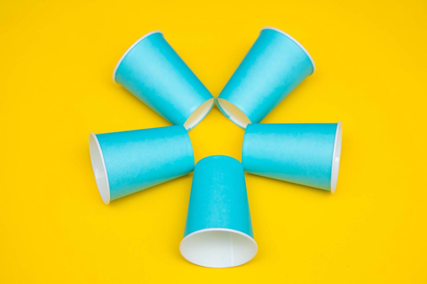 Pattern from blue paper disposable cups on yellow background photo