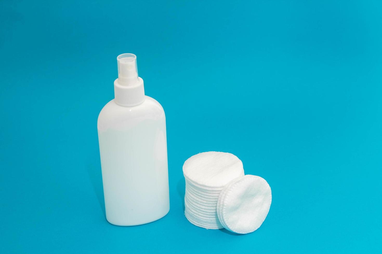 Cotton pads and plastic bottle on blue background photo