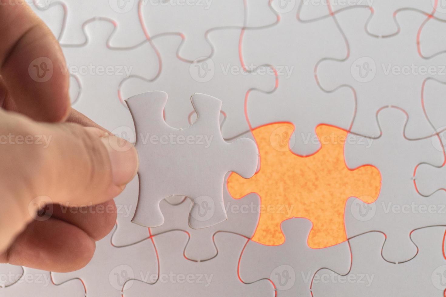 A hand hold the missing piece of white puzzle photo