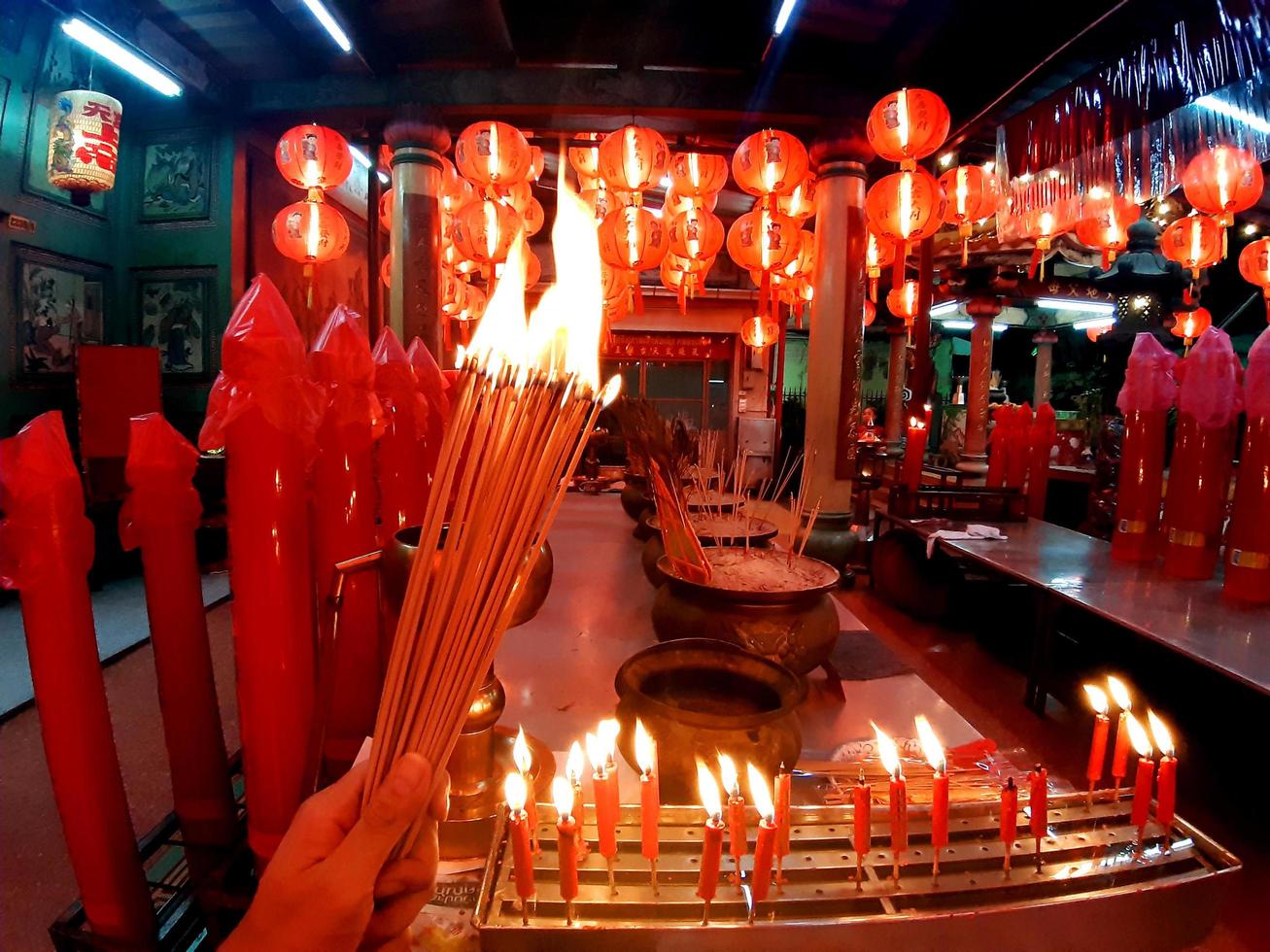 Quema de incienso en el santuario deseando buena suerte, en un santuario con velas, linternas rojas, cultura asiática foto