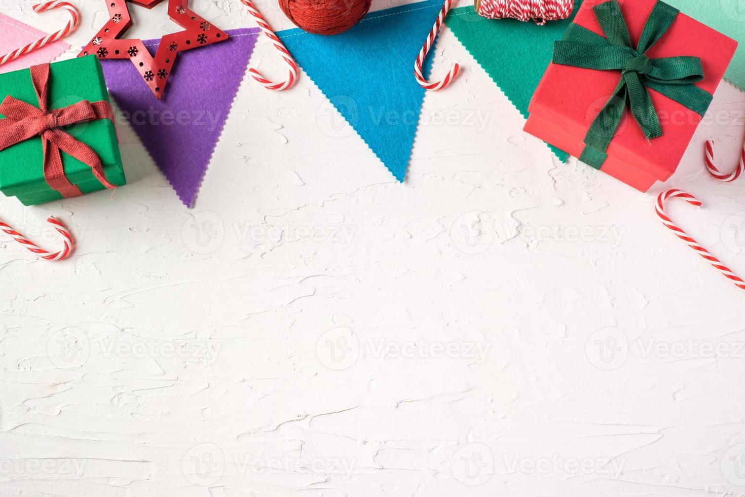 Vista superior de la colorida bandera del partido de Navidad y caja de regalo en la mesa de hormigón blanco paster foto