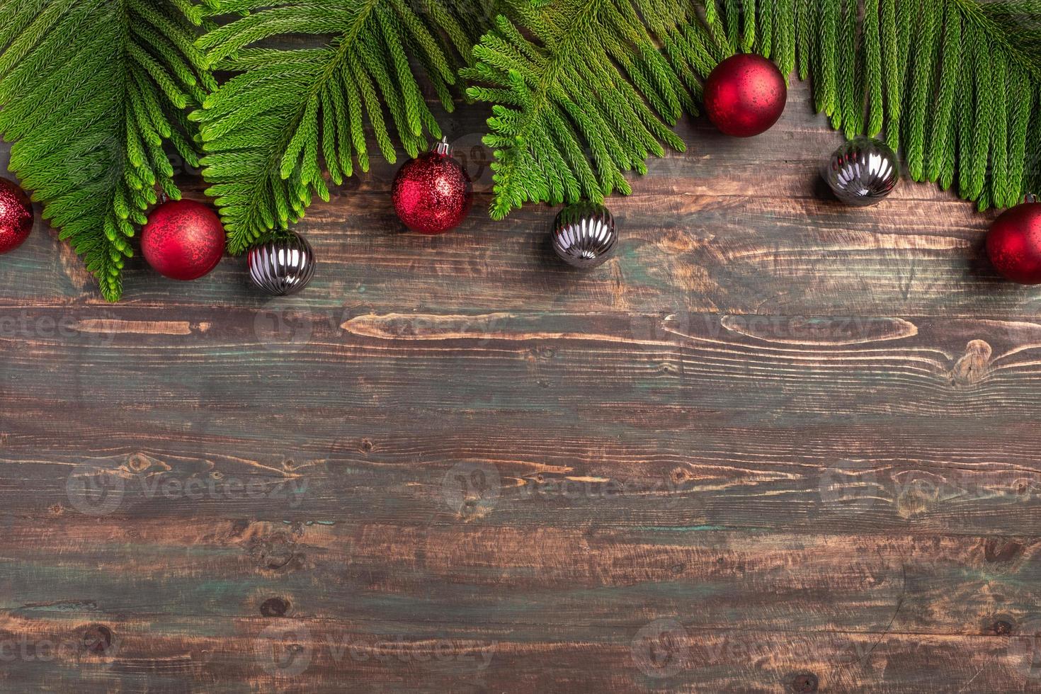 Hoja de pino de Navidad con decoración de adornos rojos sobre mesa de madera foto