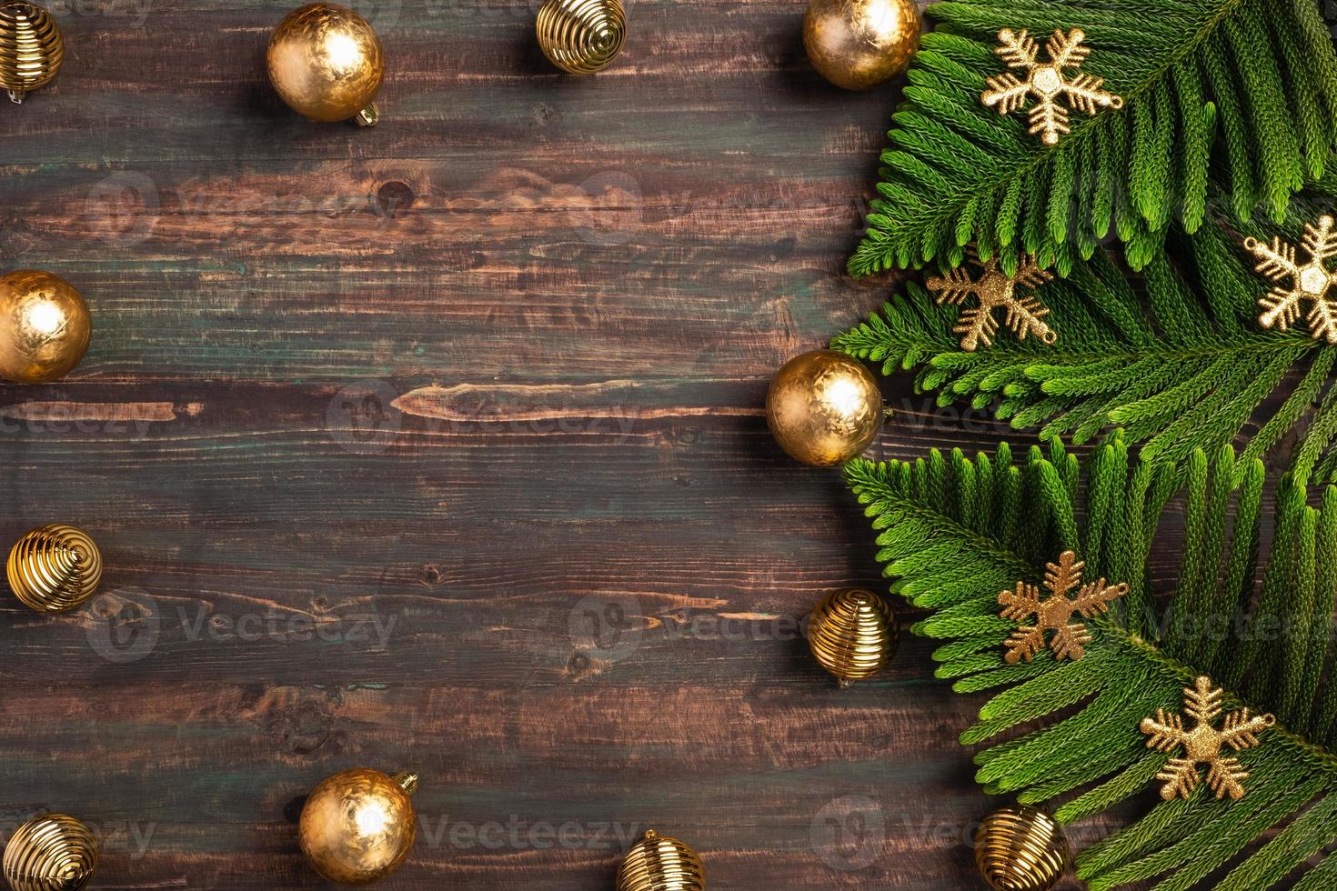 Hoja de pino de navidad con adornos dorados sobre mesa de madera foto