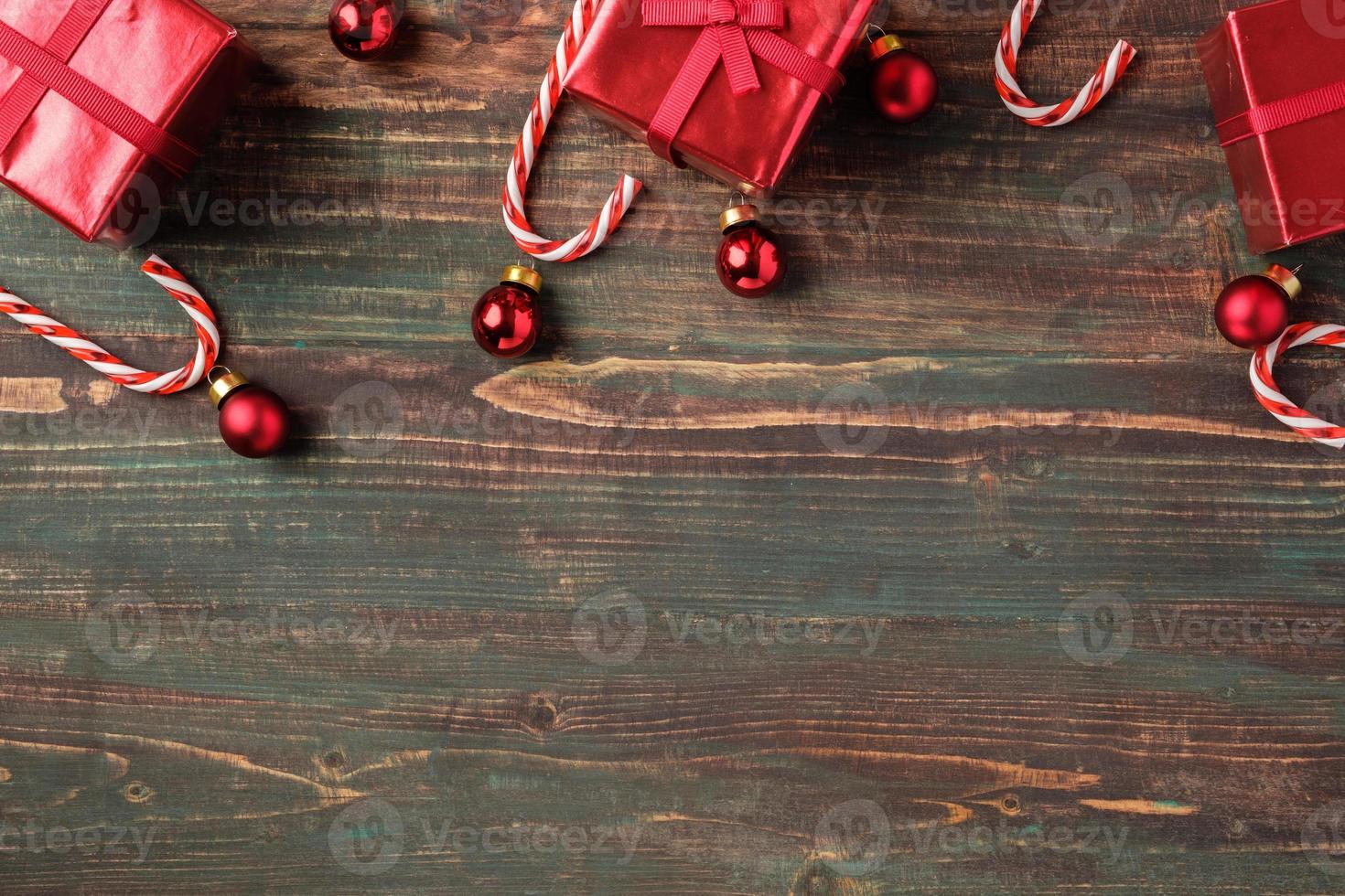 Adorno navideño rojo, caja de regalo, decoración de bastón de caramelo sobre fondo de madera de mesa foto