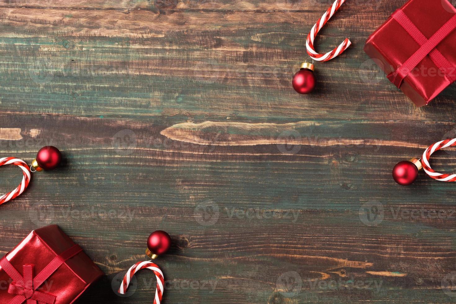 Adorno navideño rojo, caja de regalo, decoración de bastón de caramelo sobre fondo de madera de mesa foto