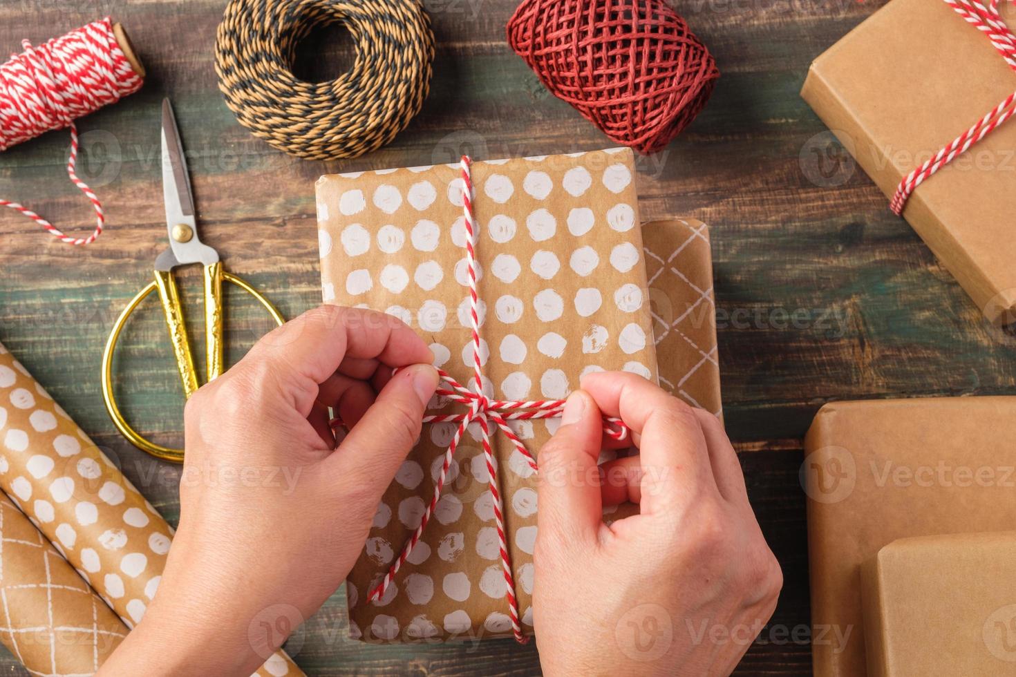 Cuerda atada a mano en caja de regalo de navidad con decoración de papel marrón con pino abeto en mesa de madera foto