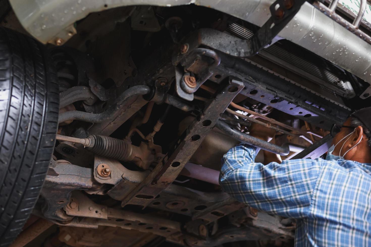 The mechanic is checking the undercarriage of the car. photo