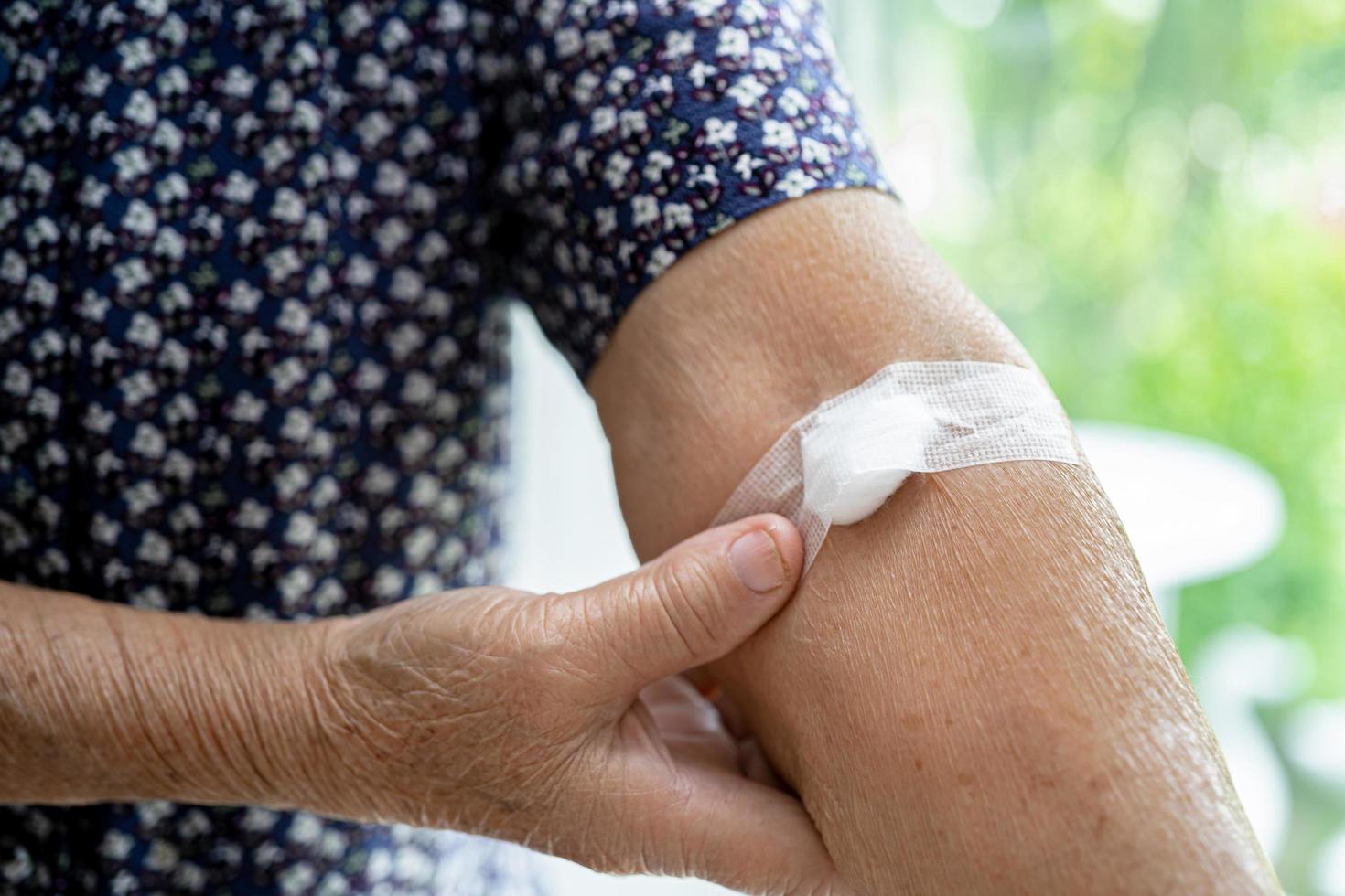 Paciente asiático mayor o anciana anciana mostrar algodón detener el sangrado, después de la prueba de extracción de sangre para un chequeo de salud físico anual para controlar el colesterol, la presión arterial y el nivel de azúcar. foto