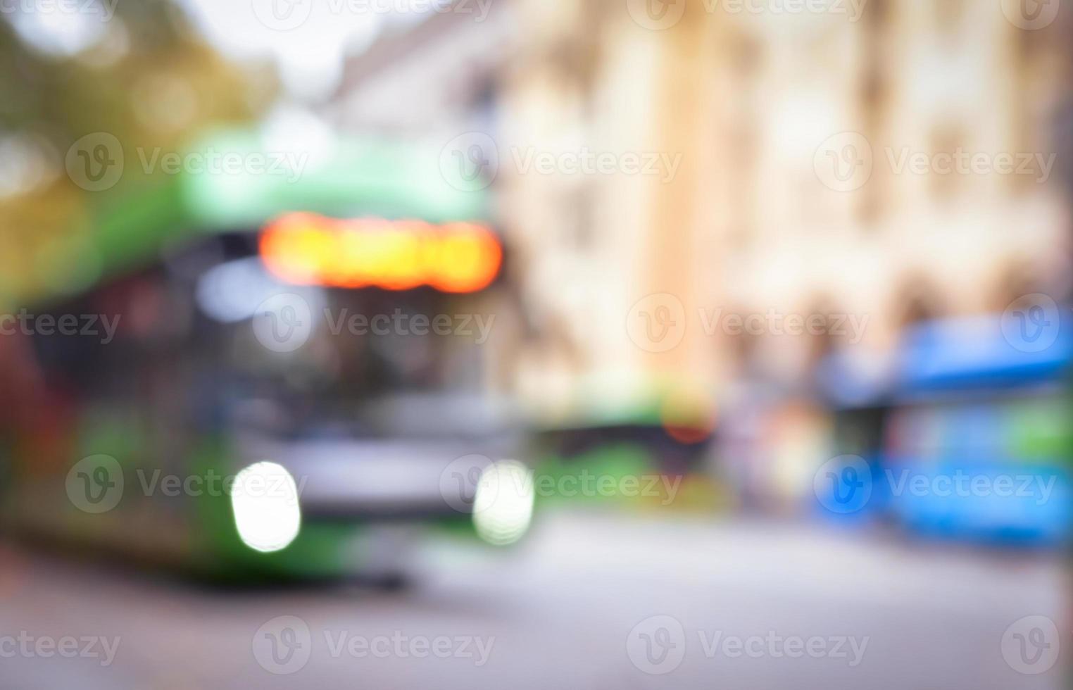 Blurred Defocused green bus with lights on in City center busy Road in overcast day . Blurry blank space public transport background photo