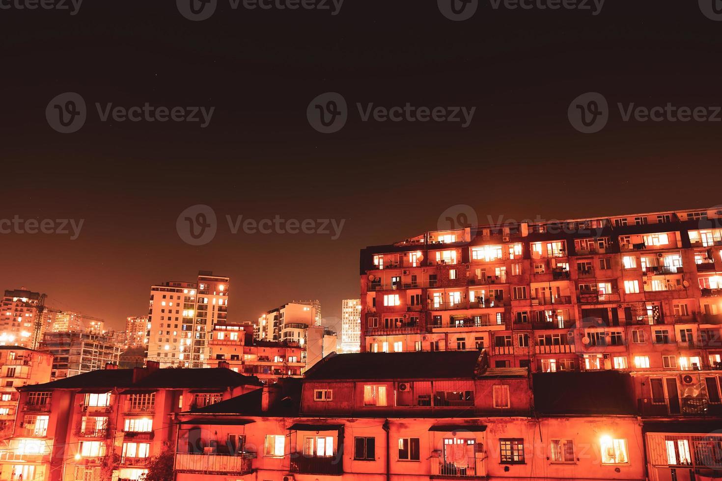 Antiguos edificios de propiedad inmobiliaria soviética en la noche en la capital, Tbilisi, con luces apagadas por la noche time-lapse con fondo de espacio de copia foto