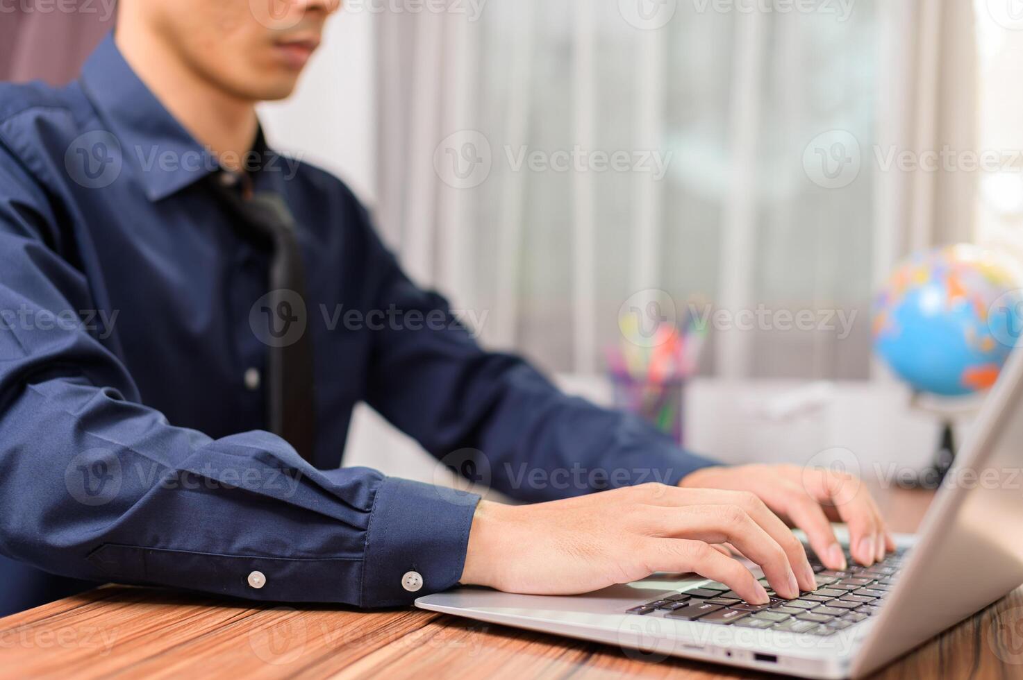 A man sitting at a desk using a laptop computer photo