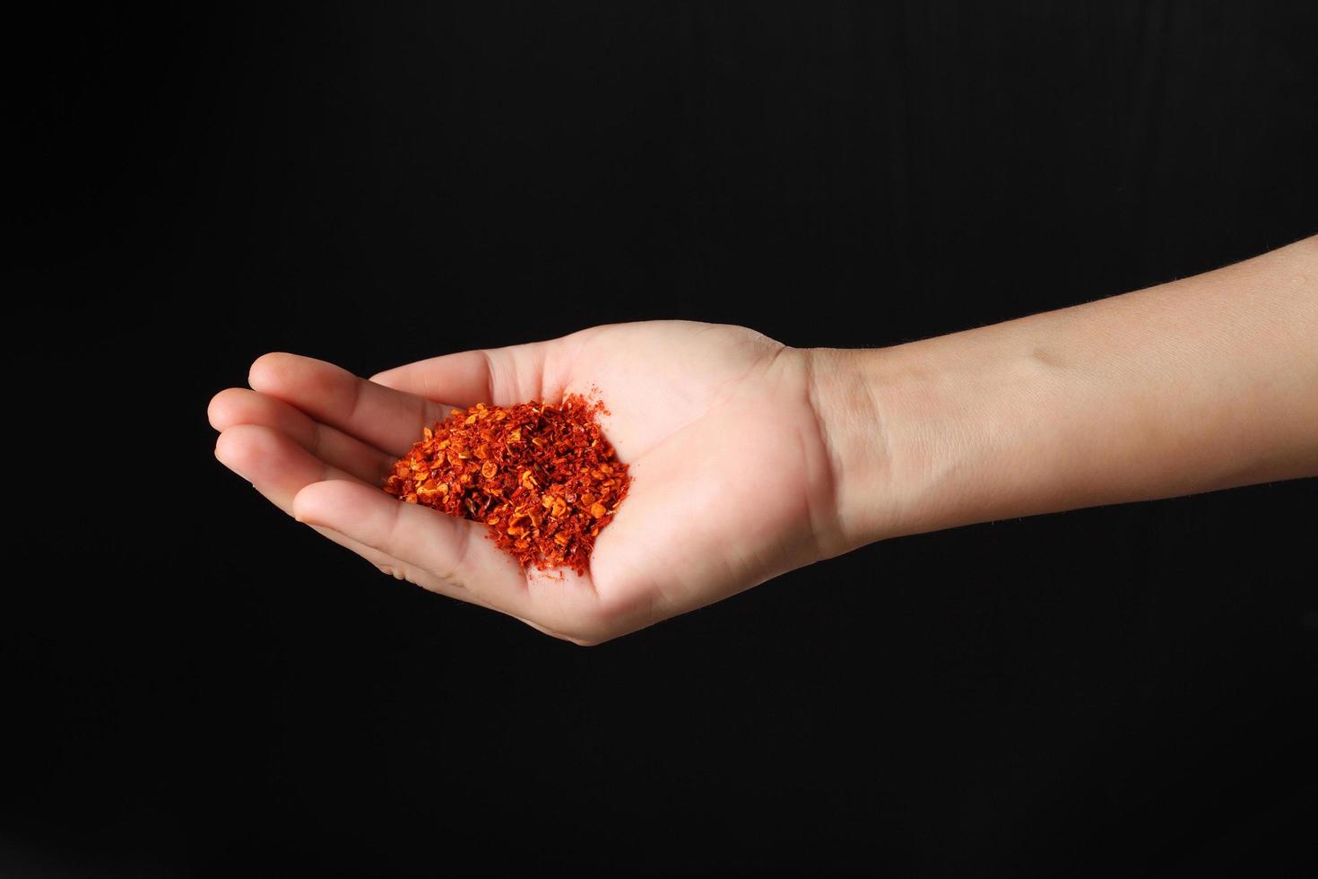 Hand holding cayenne pepper on black background photo