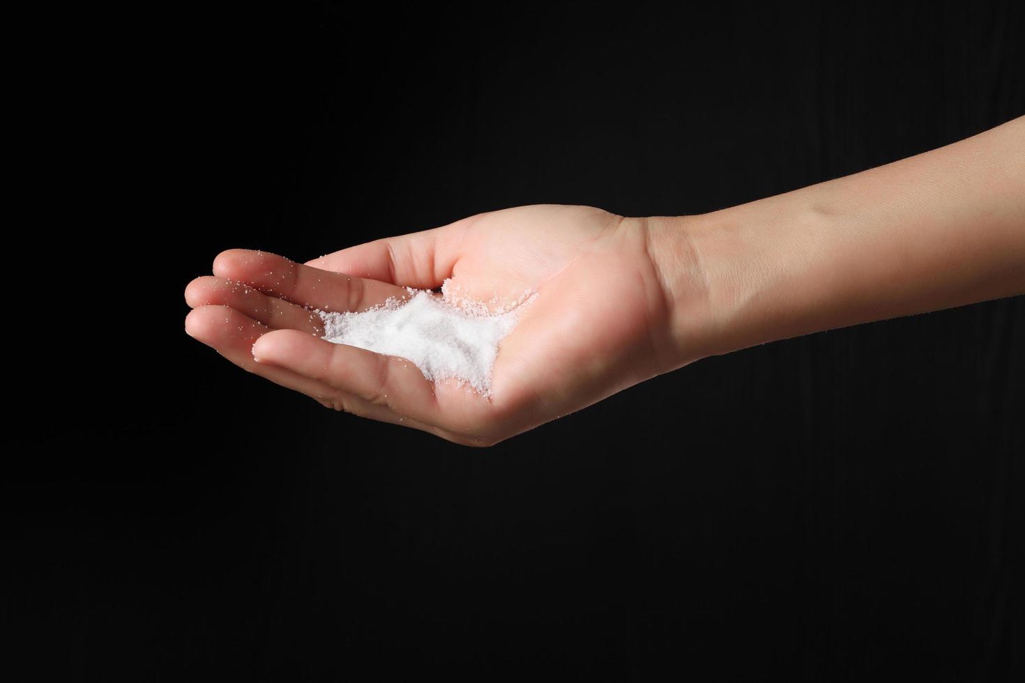 Hand holding sea salt on black background photo