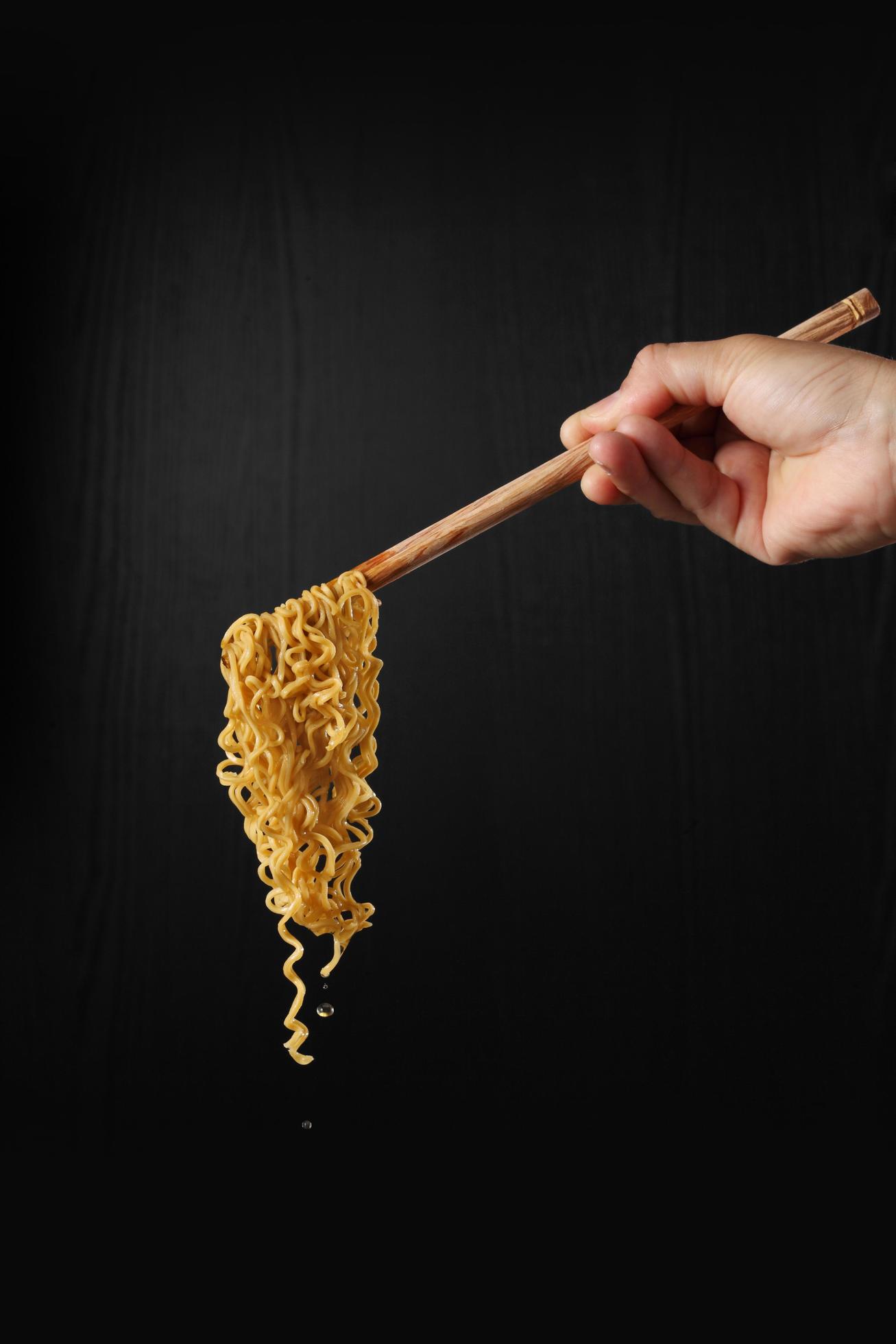 Hand holding chopsticks and noodles on black background 4732516 Stock