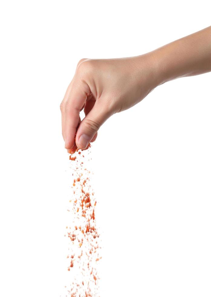 Hand sprinkling cayenne pepper on white background photo