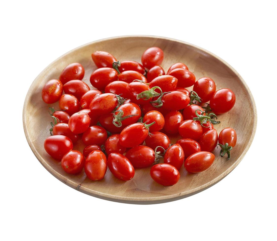 Grupo de tomate en bandeja de madera sobre fondo blanco. foto