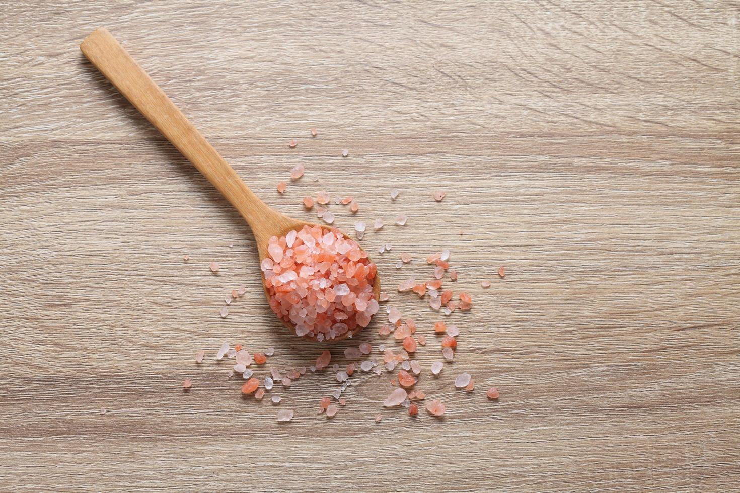 Himalayan pink salt in wooden spoon on table photo