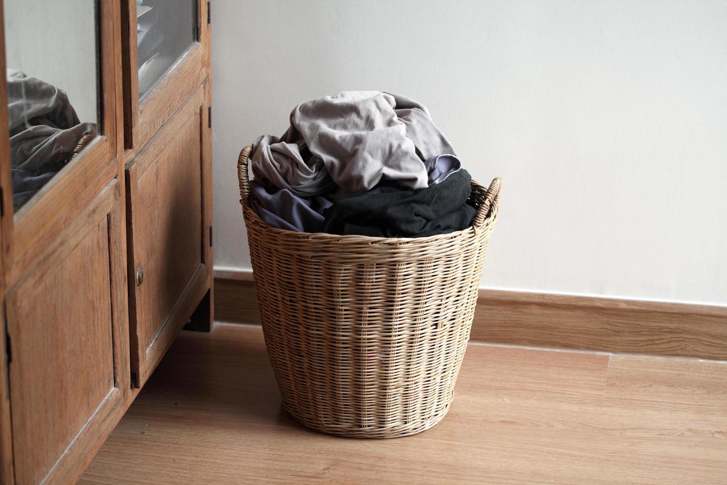 Wooden basket with dirty laundry on floor photo