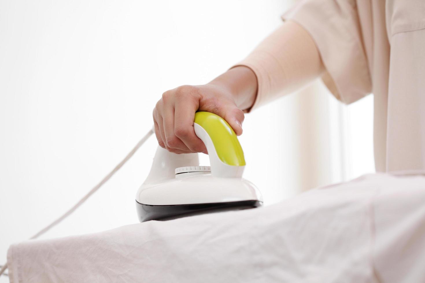 Female hand ironing cotton clothes in home photo
