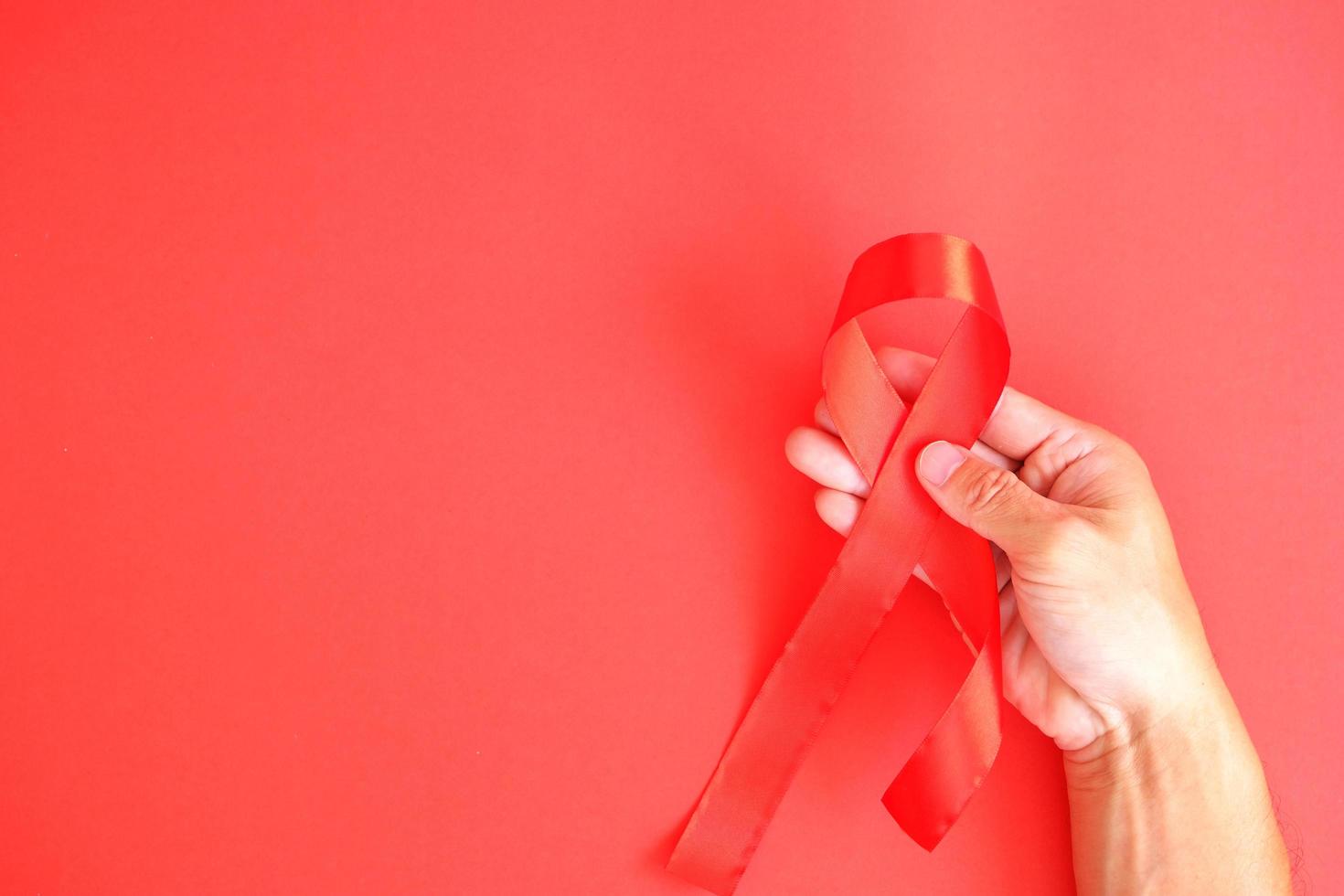 The red ribbon is an international sign of HIV and AIDS awareness, with individuals wearing red ribbons to show support for those who are living with the disease photo