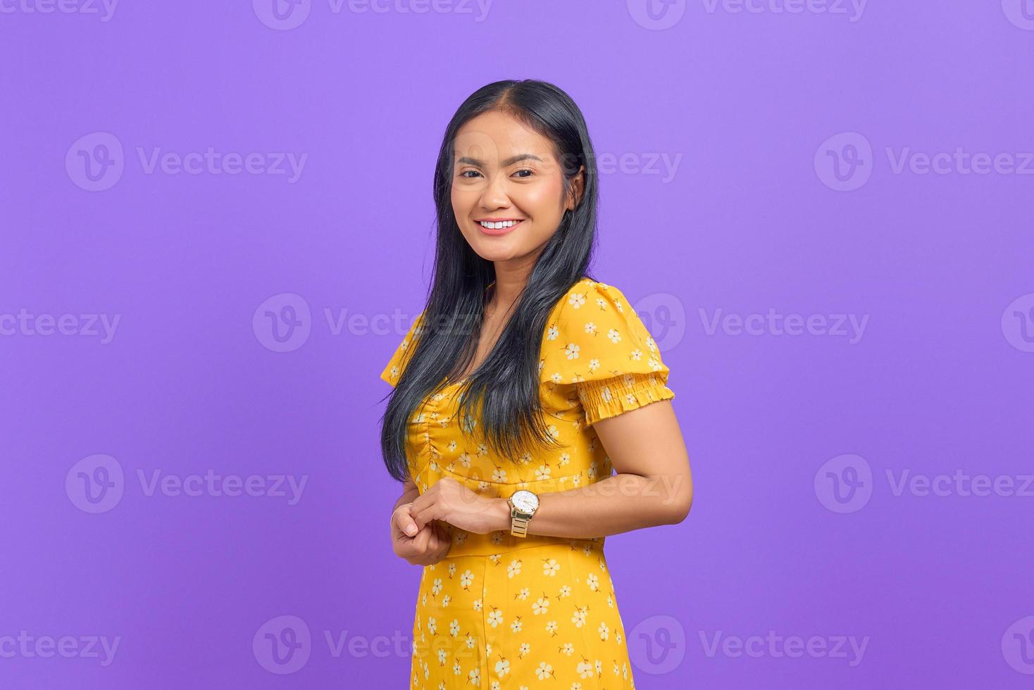 Sonriente joven asiática mantiene la mano junta y se siente optimista sobre fondo púrpura foto