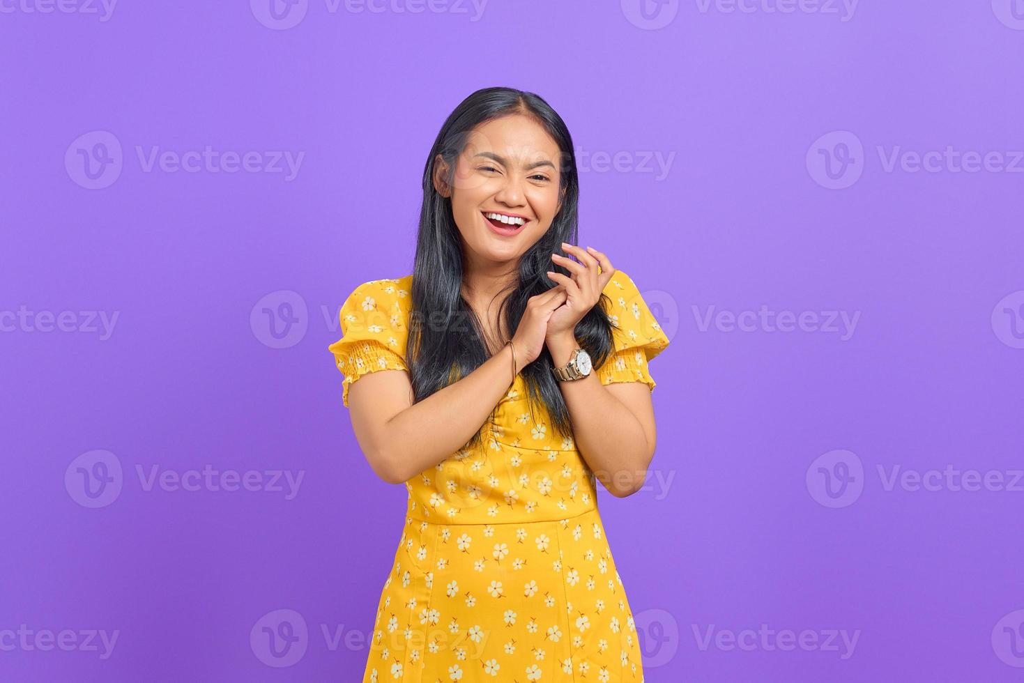 Smiling young Asian woman rub hands and looking at camera on purple background photo