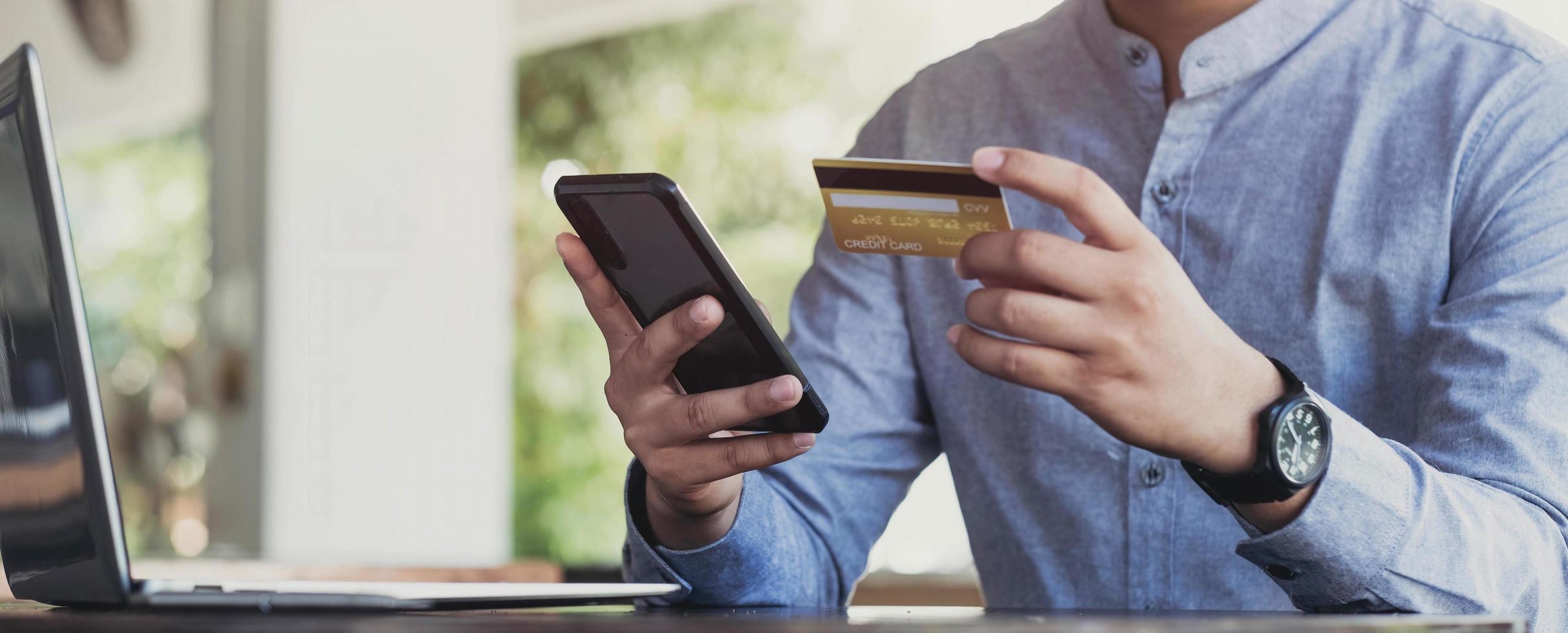 pago en línea, manos del hombre sosteniendo el teléfono inteligente y usando tarjeta de crédito para compras en línea. concepto de cyber monday foto