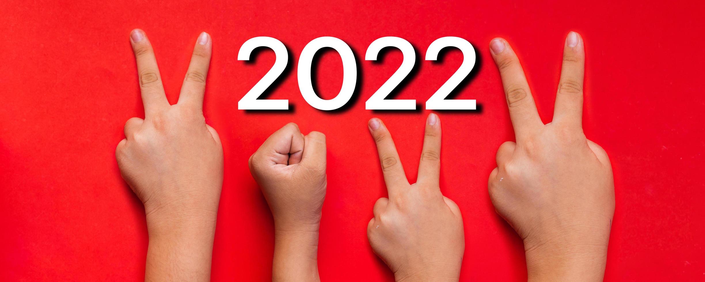 idea y creativo en 2022, símbolo de la mano del dedo del número de año nuevo sobre fondo rojo foto