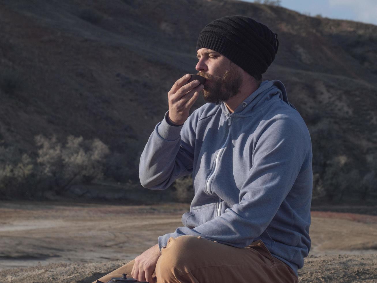man with a beard and in a knitted hat drinks tea photo