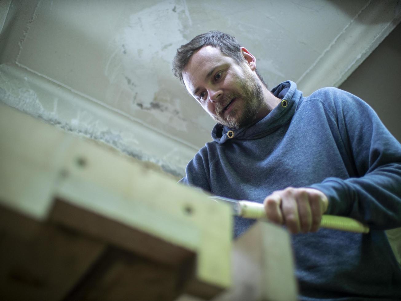 woodworker with a beard sawing photo