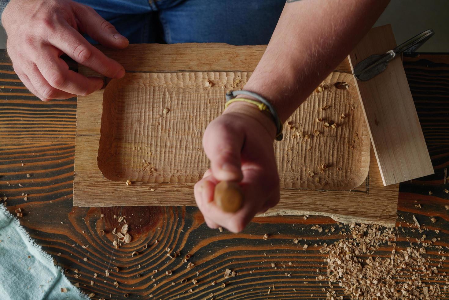 Woodcarver procesa una tabla de madera de nogal con un cincel foto