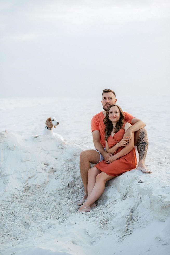 young couple in orange clothes with dog photo