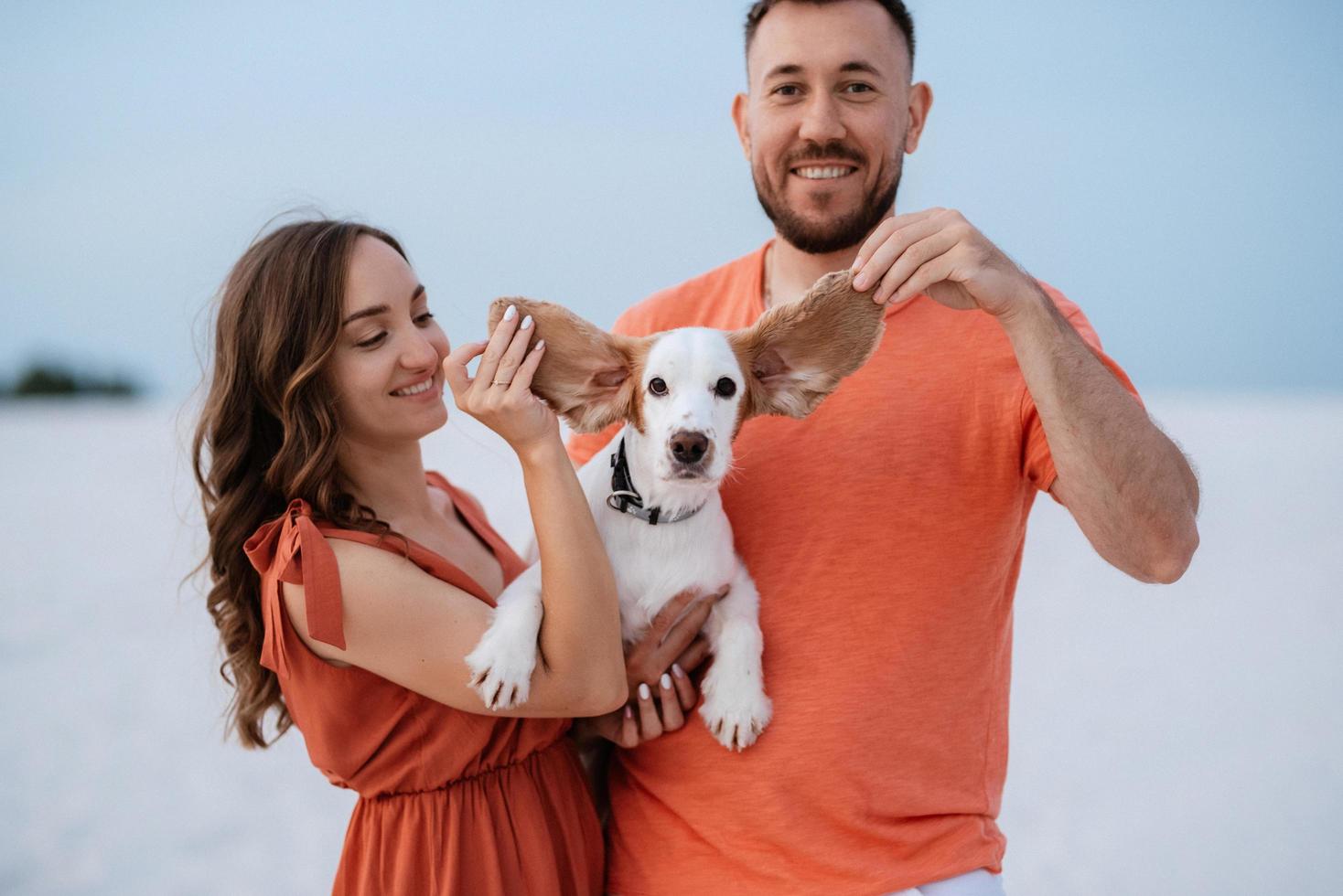 young couple in orange clothes with dog photo