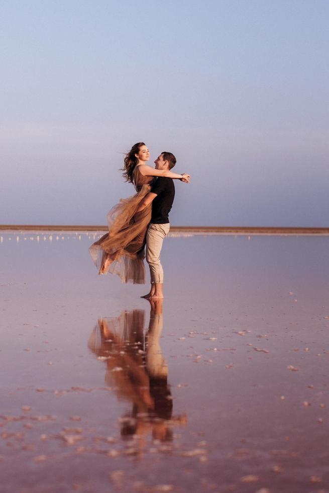 girl and a guy on the shore of a pink salt lake photo