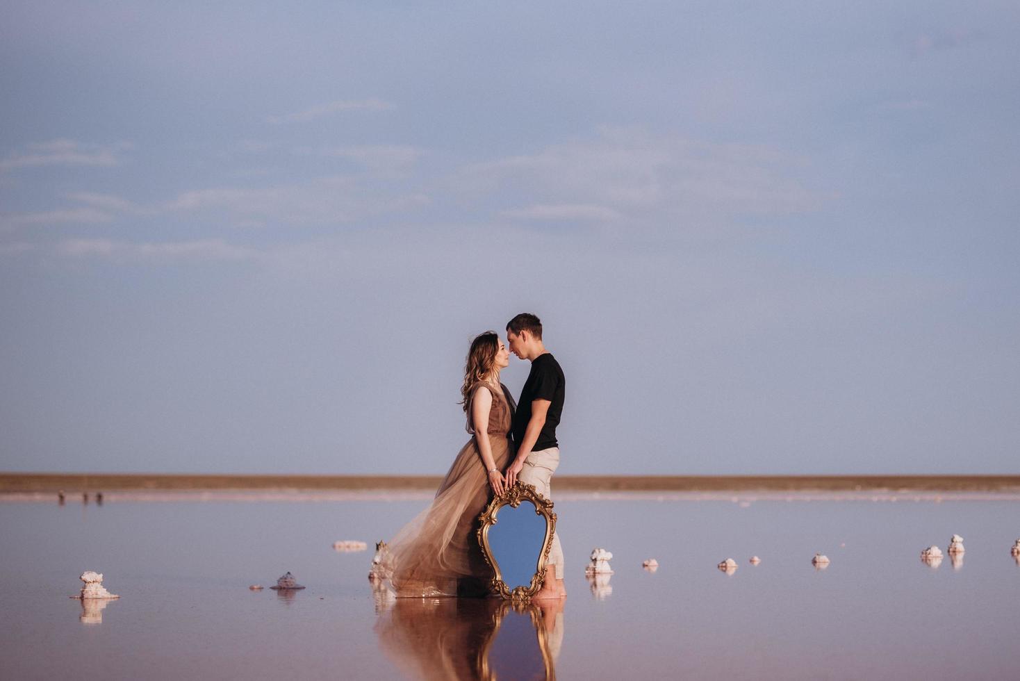 girl and a guy on the shore of a pink salt lake photo