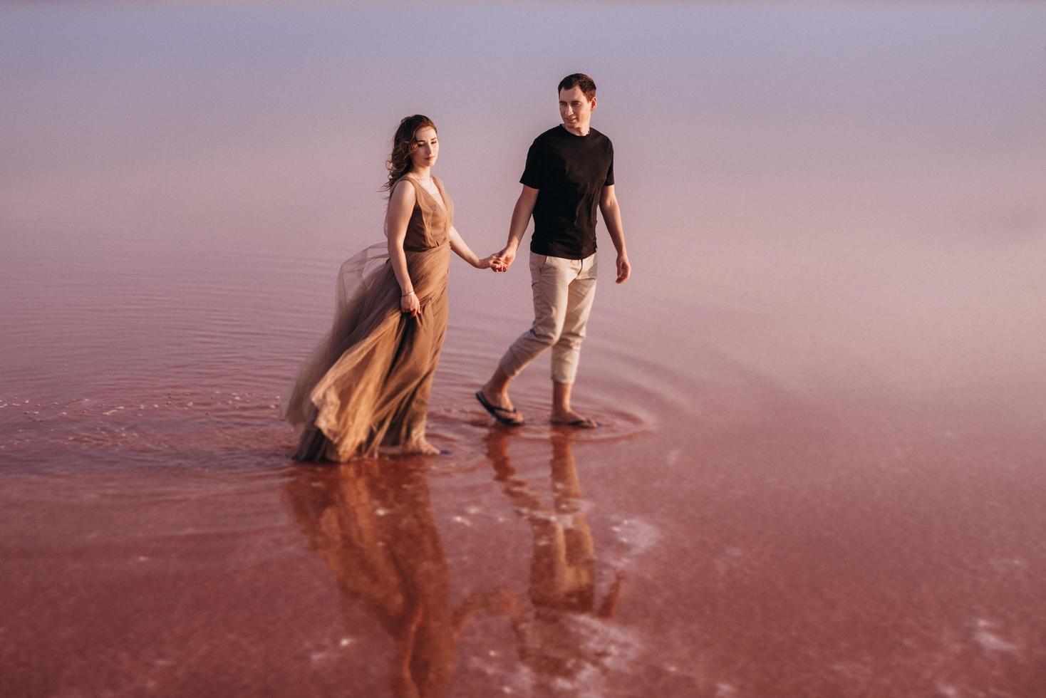 girl and a guy on the shore of a pink salt lake photo