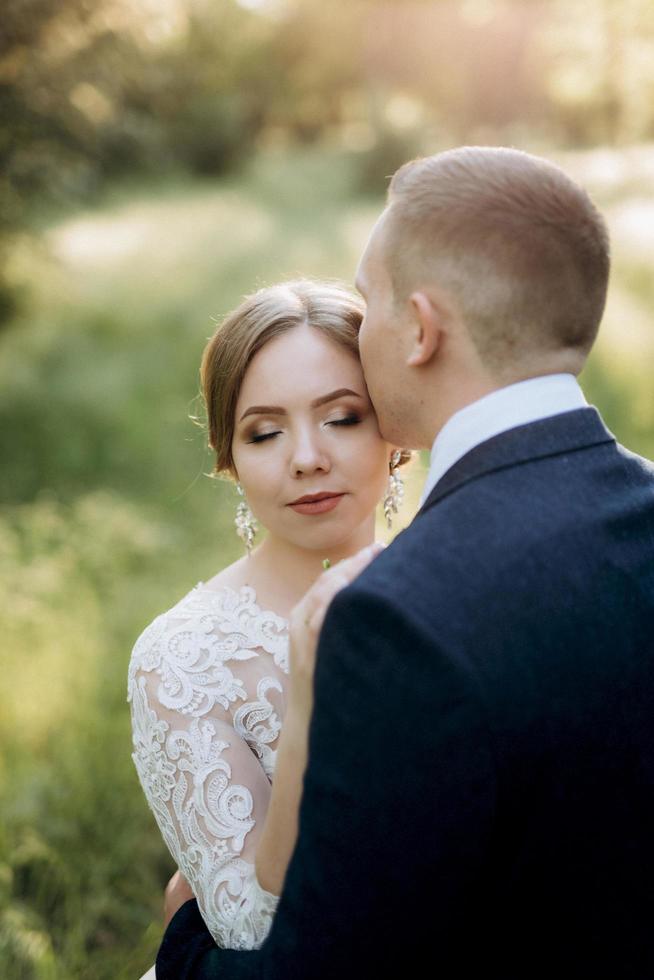 the groom and the bride are walking in the forest near a narrow river photo