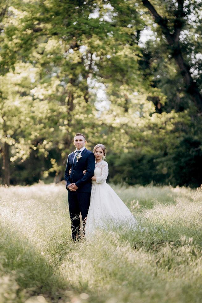 the groom and the bride are walking in the forest near a narrow river photo