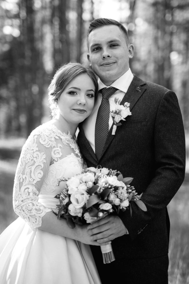 the bride and groom are walking in a pine forest photo