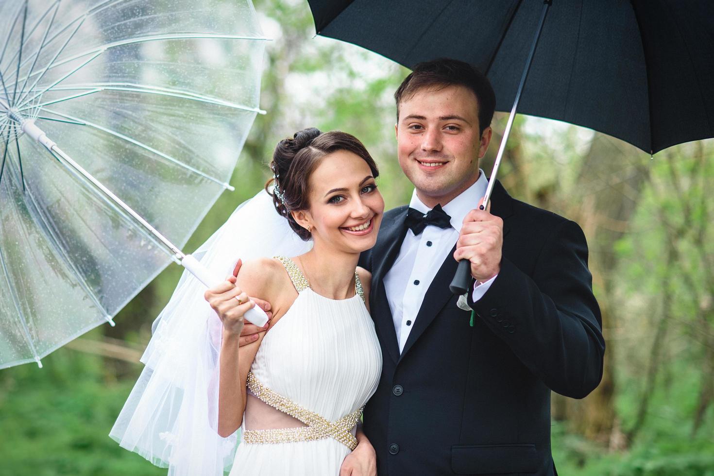 la novia y el novio en un día lluvioso de boda caminando foto