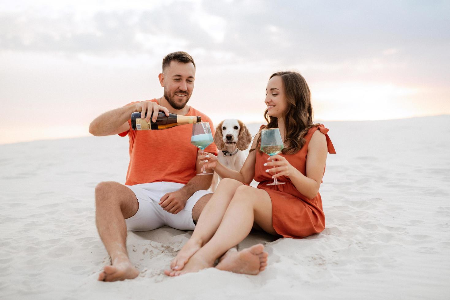 young couple in orange clothes with dog photo