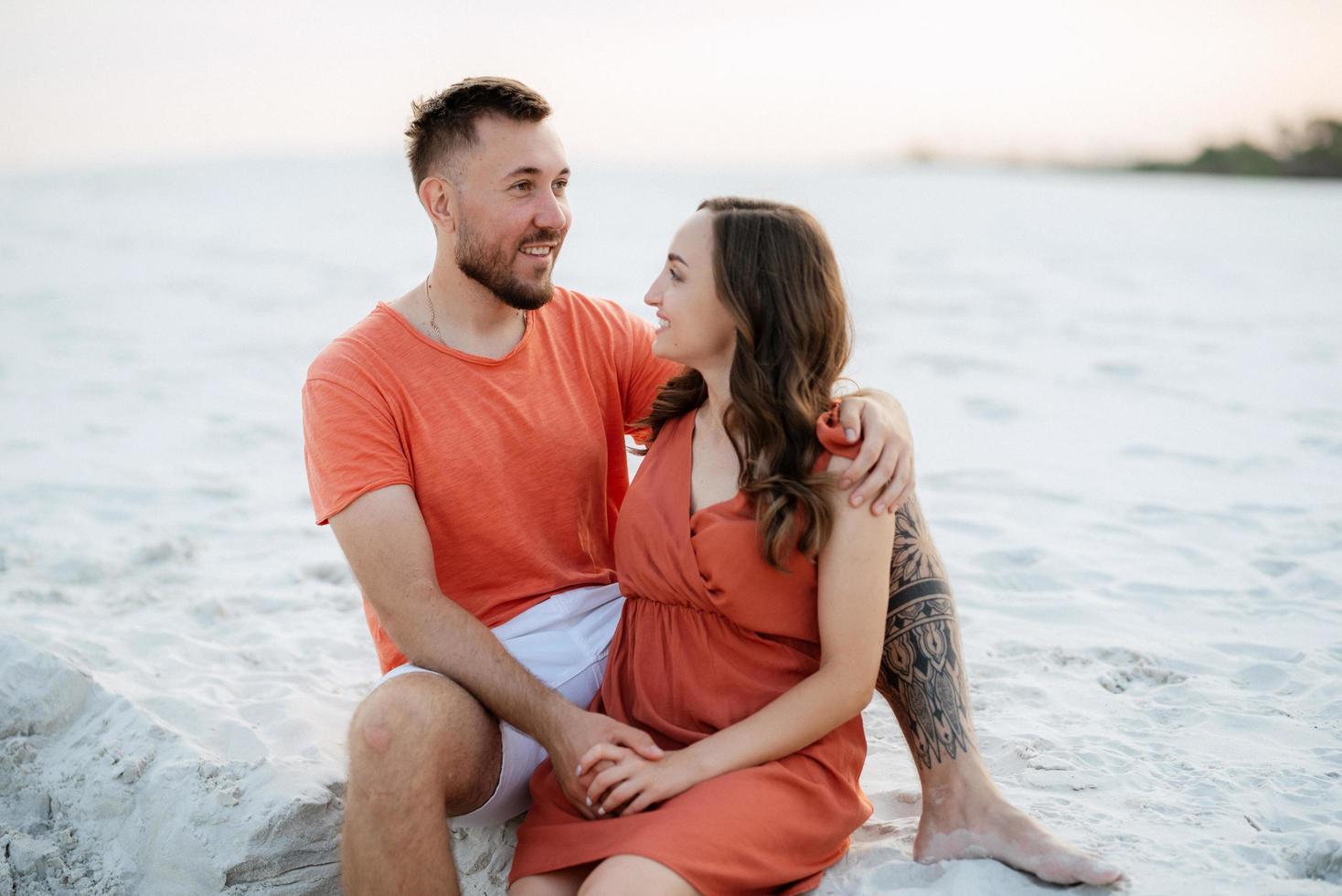 young couple in orange clothes with dog photo