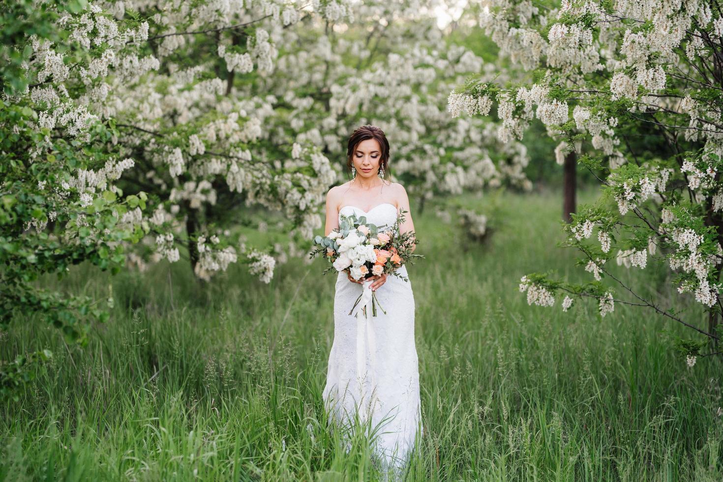 novia con un vestido blanco con un gran ramo de primavera foto