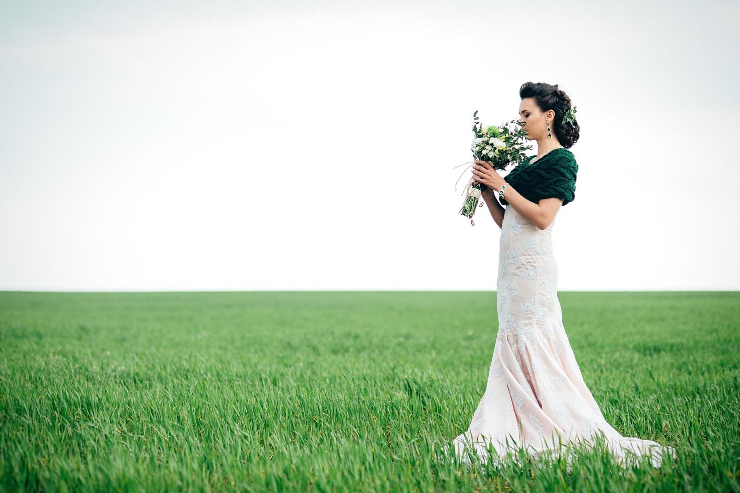 novia con un ramo de flores con un vestido de marfil y un chal de punto foto