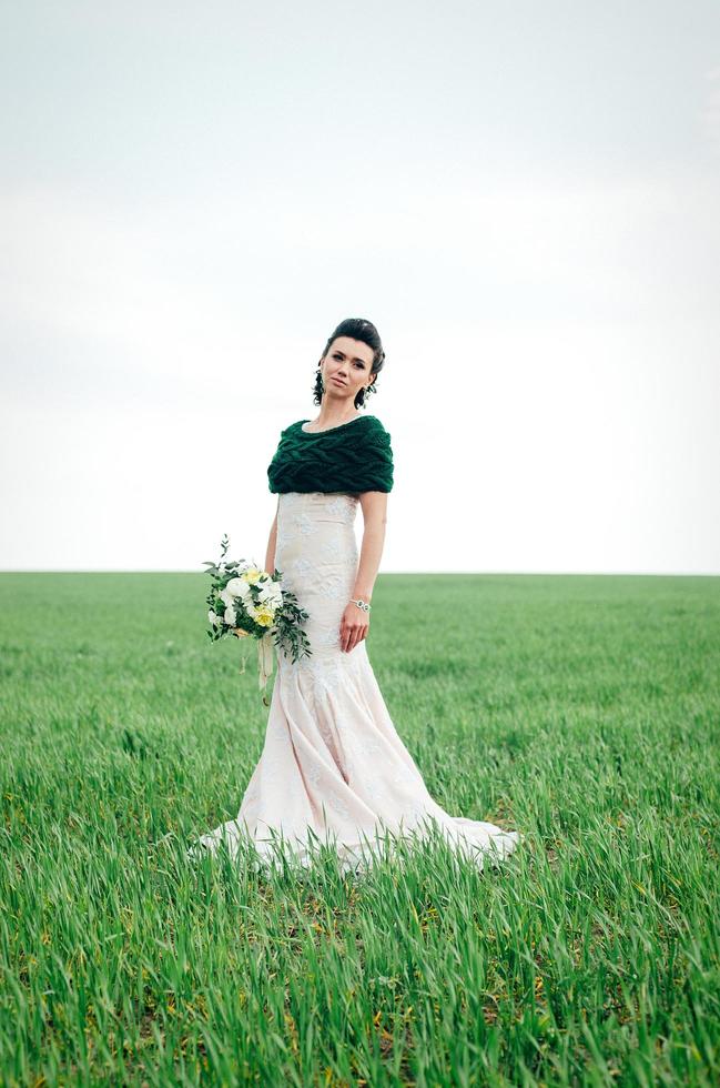 bride with a bouquet in an ivory dress and a knitted shawl photo