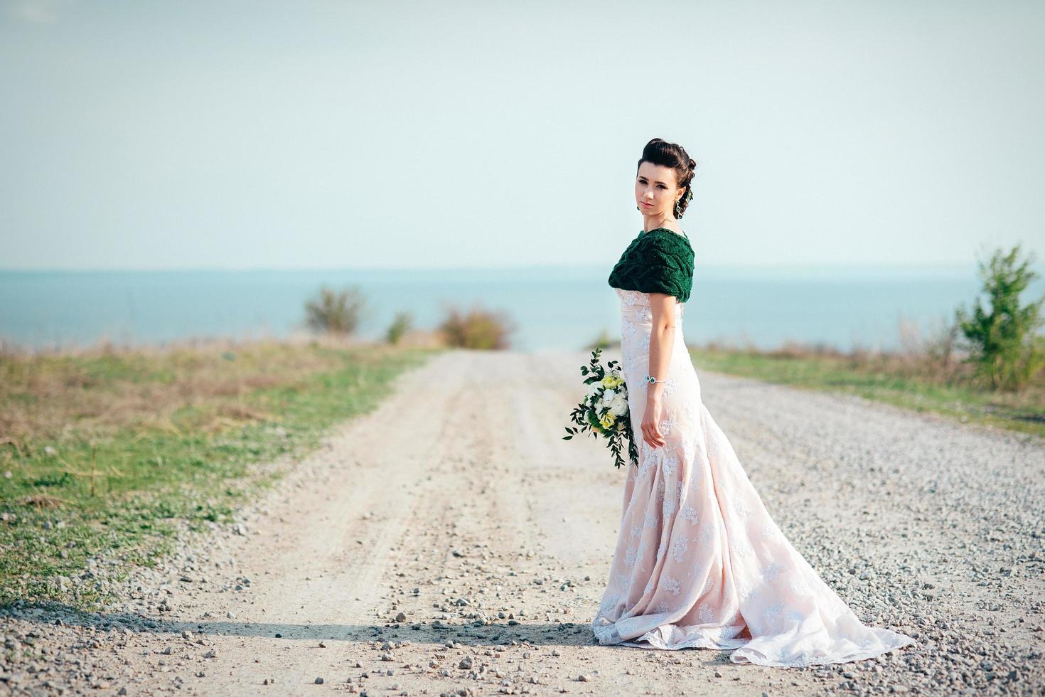 bride with a bouquet of flowers in an ivory dress and a knitted shawl photo
